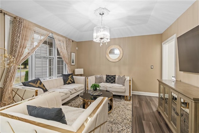 living room with a tray ceiling, dark wood-type flooring, and a notable chandelier