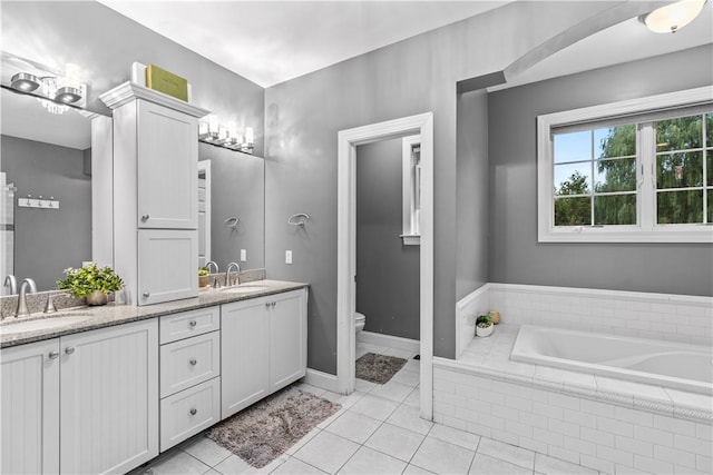 bathroom featuring toilet, vanity, a relaxing tiled tub, and tile patterned floors