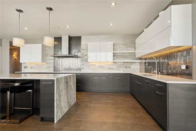 kitchen with white cabinetry, sink, wall chimney exhaust hood, pendant lighting, and decorative backsplash