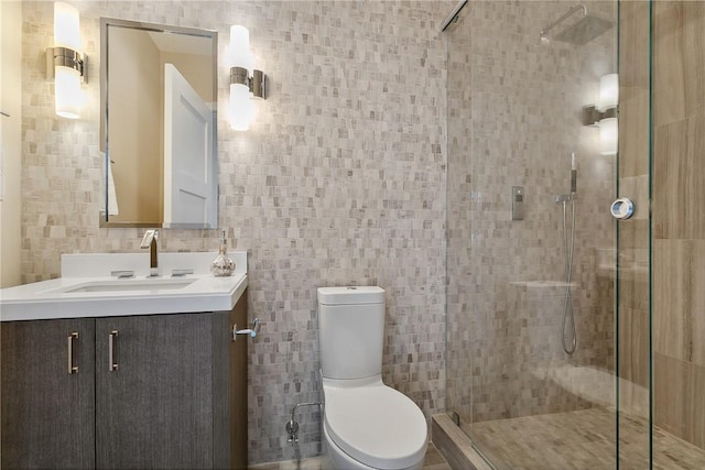 bathroom with vanity, toilet, a shower with door, and tile walls