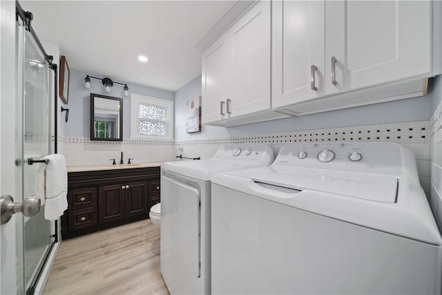 laundry room with light hardwood / wood-style flooring, washer and clothes dryer, and sink