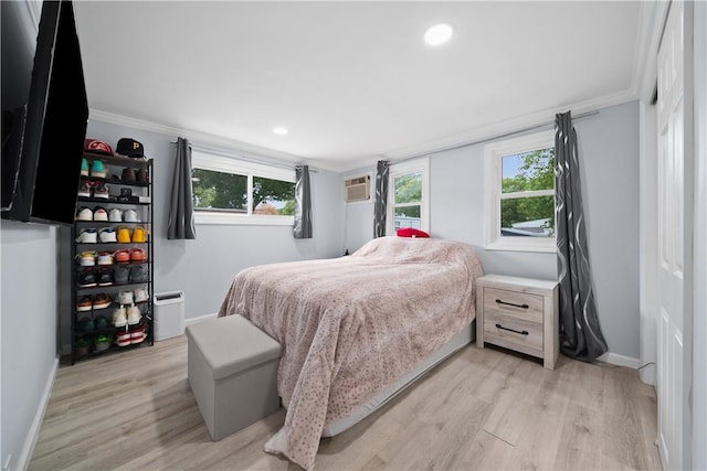 bedroom featuring an AC wall unit, crown molding, and light wood-type flooring