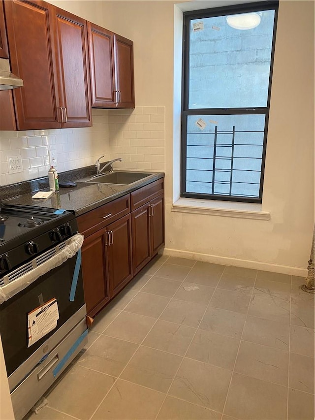 kitchen featuring sink, tasteful backsplash, stainless steel range oven, dark stone counters, and light tile patterned flooring