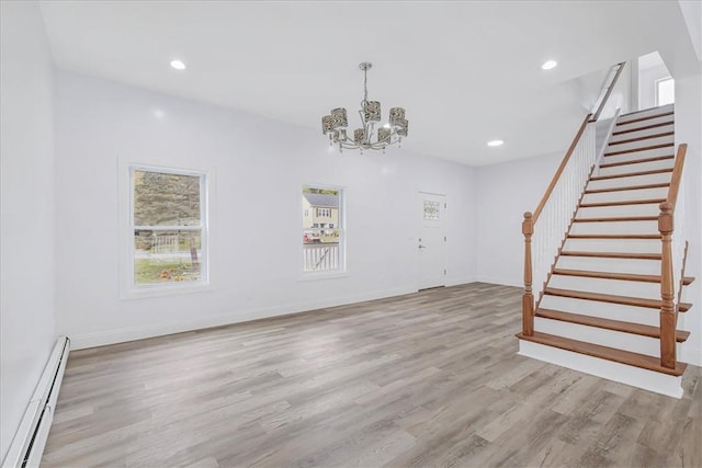 unfurnished living room featuring a baseboard heating unit, light hardwood / wood-style flooring, and a healthy amount of sunlight