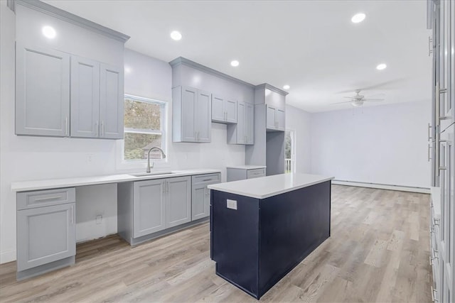 kitchen with ceiling fan, sink, baseboard heating, light hardwood / wood-style floors, and a kitchen island