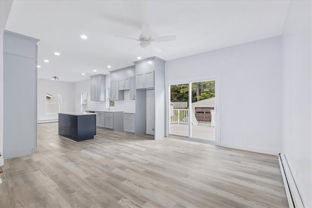 unfurnished living room featuring baseboard heating, ceiling fan, and light hardwood / wood-style flooring