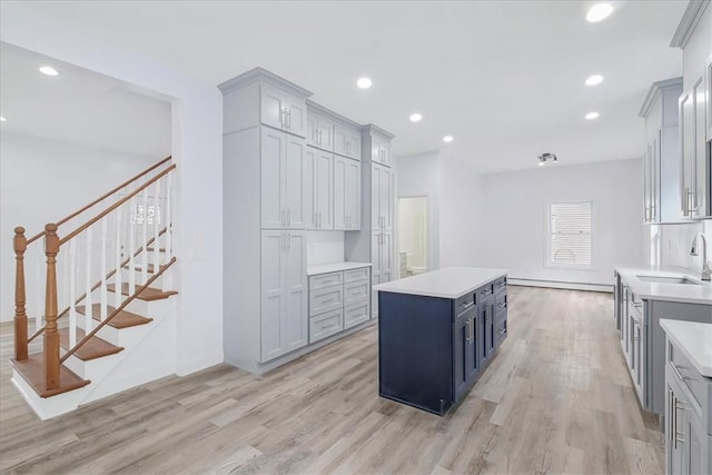 kitchen featuring gray cabinetry, a kitchen island, light hardwood / wood-style floors, and sink