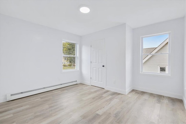 unfurnished room with light wood-type flooring, a wealth of natural light, and a baseboard radiator