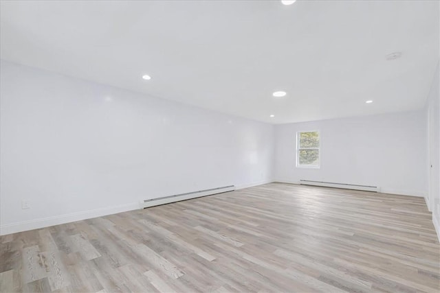 empty room with light hardwood / wood-style floors and a baseboard heating unit