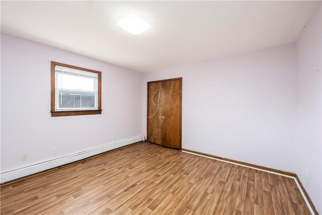 empty room featuring light wood-type flooring and a baseboard radiator