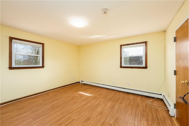 empty room with baseboard heating and light hardwood / wood-style floors