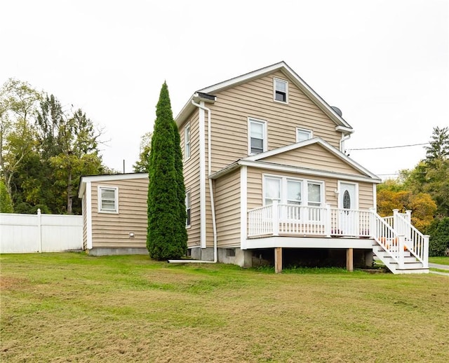 rear view of house featuring a lawn and a wooden deck