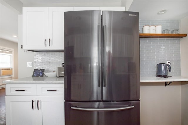 kitchen featuring cooling unit, tasteful backsplash, light stone counters, white cabinetry, and stainless steel refrigerator