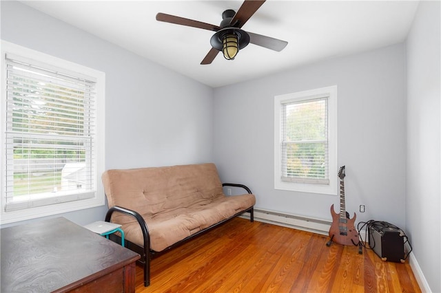 sitting room featuring baseboard heating, ceiling fan, and hardwood / wood-style flooring