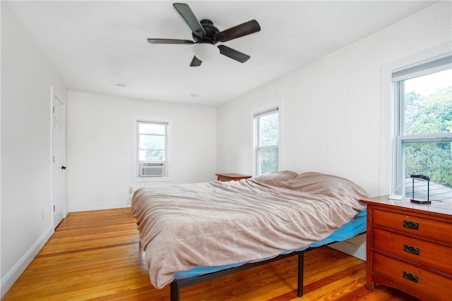 bedroom featuring ceiling fan, light wood-type flooring, and multiple windows