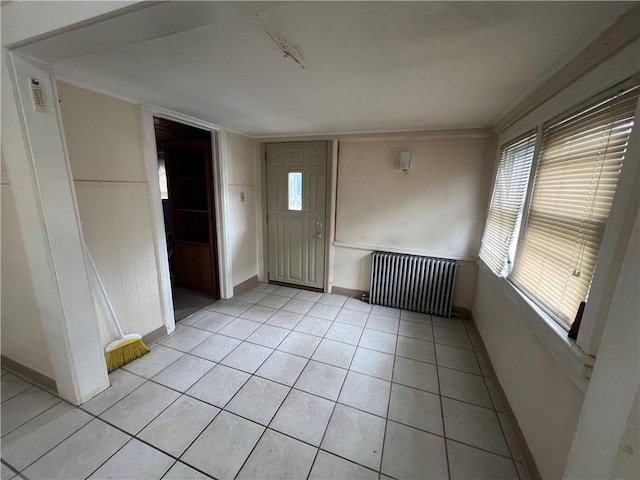 entrance foyer with radiator heating unit, light tile patterned floors, and a healthy amount of sunlight