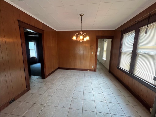 unfurnished dining area featuring crown molding, wooden walls, and a chandelier