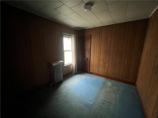 spare room with radiator heating unit and wood walls