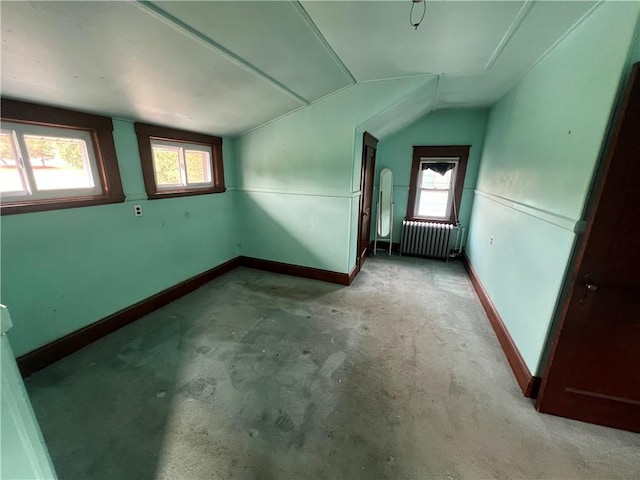 unfurnished room featuring radiator heating unit and vaulted ceiling