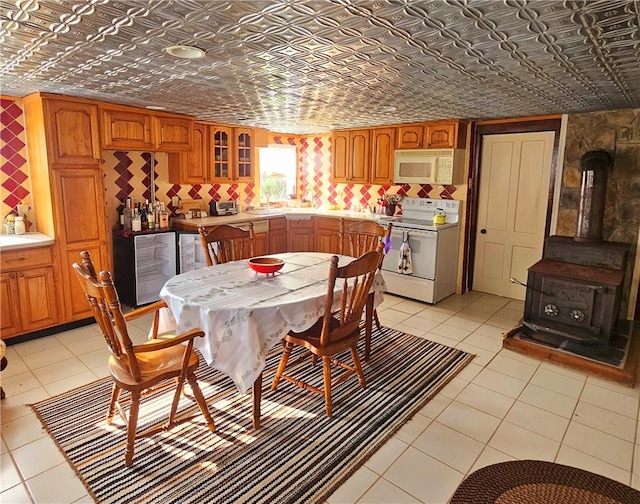 dining room with a wood stove, beverage cooler, and light tile patterned flooring