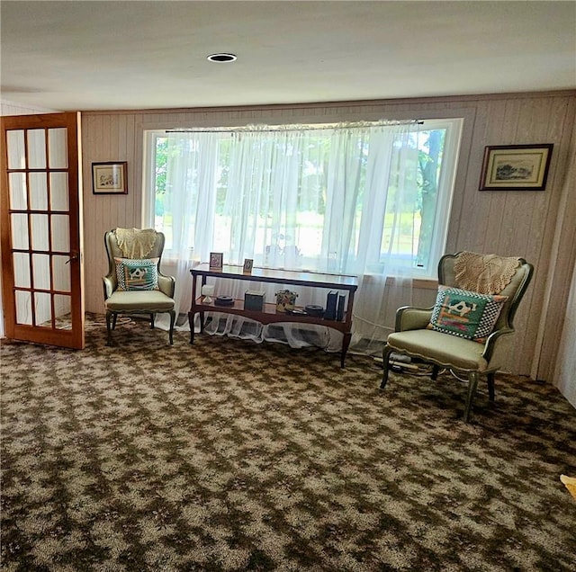 living area with carpet flooring and wooden walls