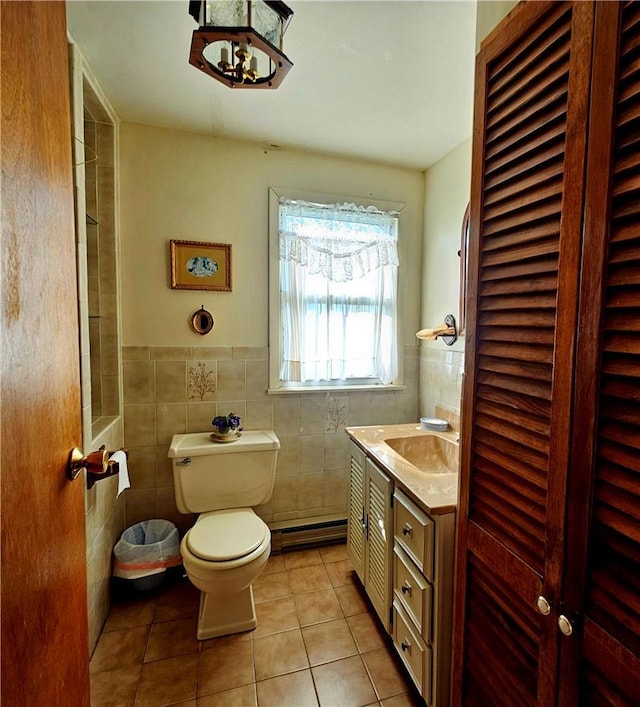 bathroom featuring a baseboard radiator, tile patterned flooring, toilet, vanity, and tile walls