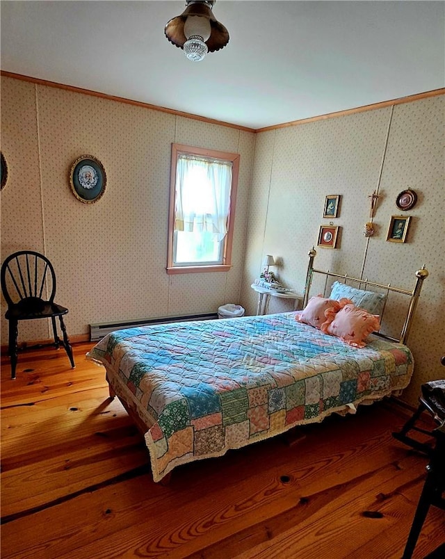 bedroom with hardwood / wood-style floors, ornamental molding, and baseboard heating