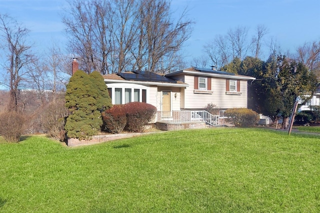 tri-level home with solar panels and a front lawn