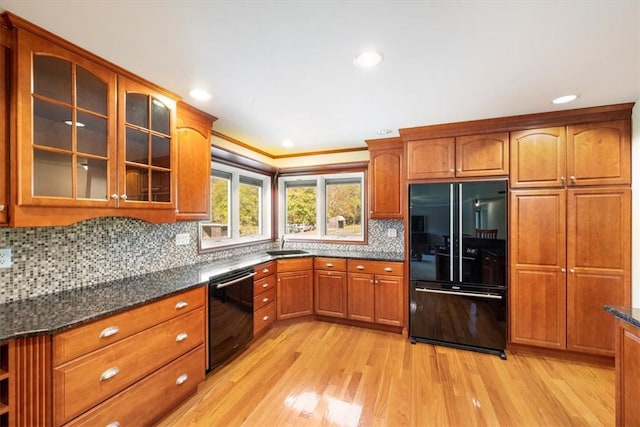 kitchen with backsplash, ornamental molding, black appliances, light hardwood / wood-style flooring, and dark stone countertops