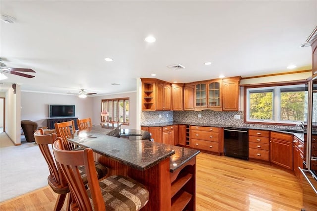 kitchen with tasteful backsplash, crown molding, a breakfast bar area, and light hardwood / wood-style floors