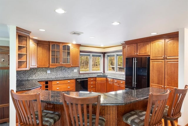 kitchen featuring backsplash, dark stone countertops, a breakfast bar, black appliances, and ornamental molding