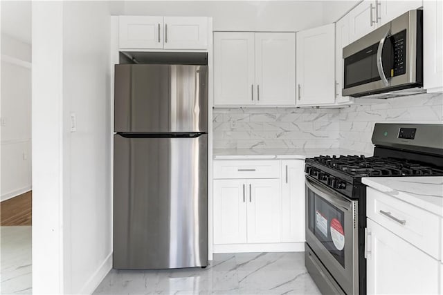 kitchen with white cabinets, light stone counters, appliances with stainless steel finishes, and tasteful backsplash