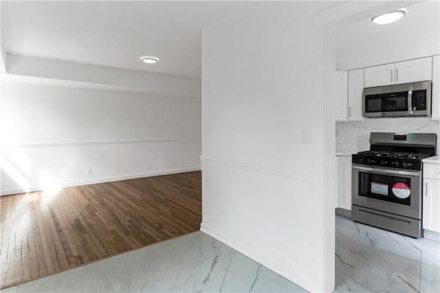 kitchen with white cabinets, light wood-type flooring, and stainless steel appliances