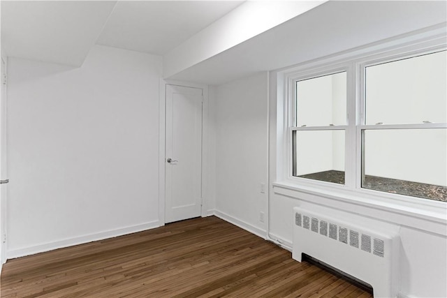 unfurnished room featuring radiator heating unit and dark wood-type flooring