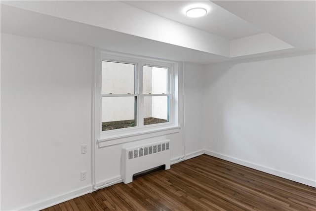 spare room featuring dark hardwood / wood-style flooring and radiator heating unit