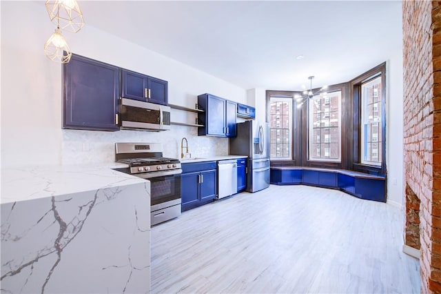 kitchen with light stone counters, hanging light fixtures, and appliances with stainless steel finishes