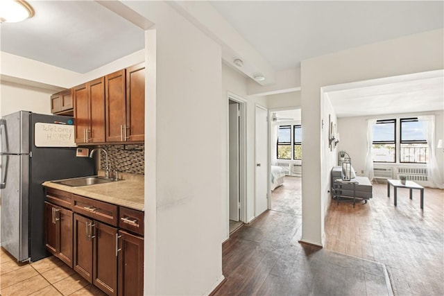 kitchen with backsplash, plenty of natural light, sink, and light hardwood / wood-style flooring