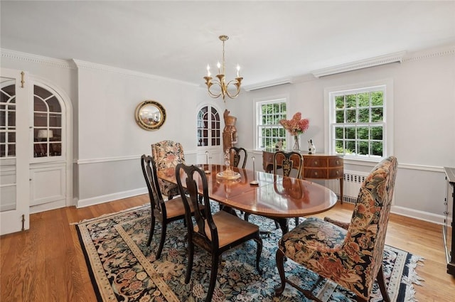 dining area with hardwood / wood-style flooring, an inviting chandelier, radiator, and ornamental molding