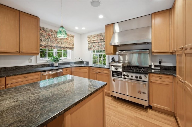 kitchen with pendant lighting, wall chimney exhaust hood, dark stone countertops, light hardwood / wood-style floors, and stainless steel appliances