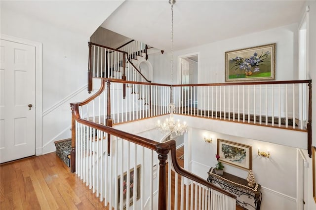 staircase featuring wood-type flooring and a notable chandelier