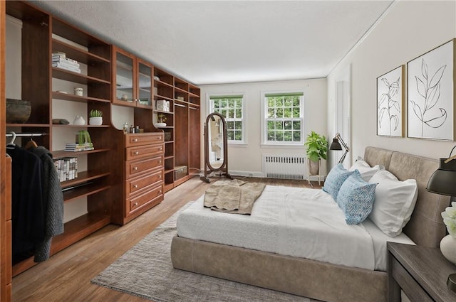 bedroom featuring radiator heating unit and light hardwood / wood-style flooring