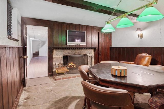 dining room with light wood-type flooring, a fireplace, and wooden walls