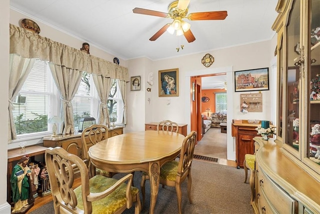 dining space with carpet flooring, ornamental molding, and a wealth of natural light