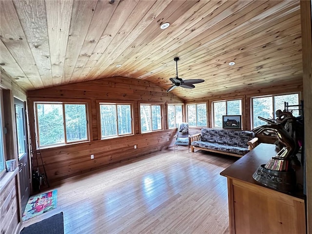 interior space with ceiling fan, wood walls, lofted ceiling, wood ceiling, and light wood-type flooring