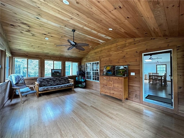 living room featuring light hardwood / wood-style floors, wooden ceiling, wooden walls, and vaulted ceiling