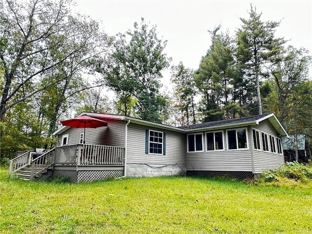 rear view of house featuring a lawn and a wooden deck