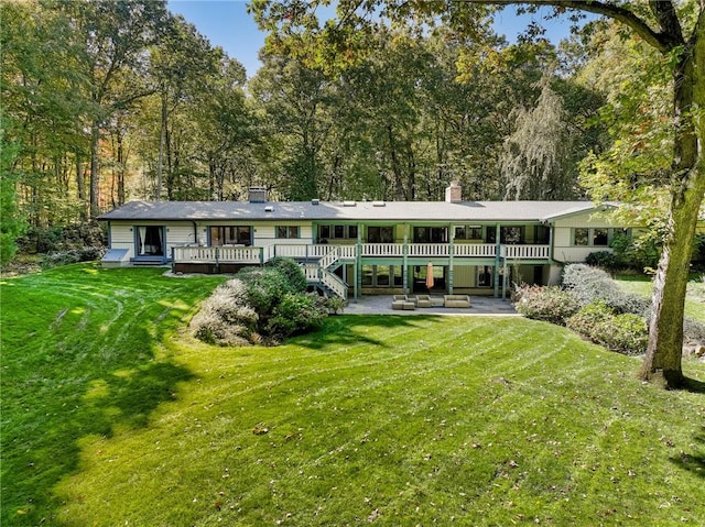 rear view of property featuring a patio, a deck, and a lawn