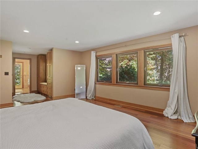 bedroom featuring light hardwood / wood-style floors, multiple windows, and ensuite bathroom