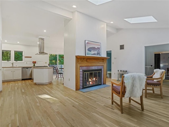 living room with light hardwood / wood-style floors, high vaulted ceiling, and a skylight