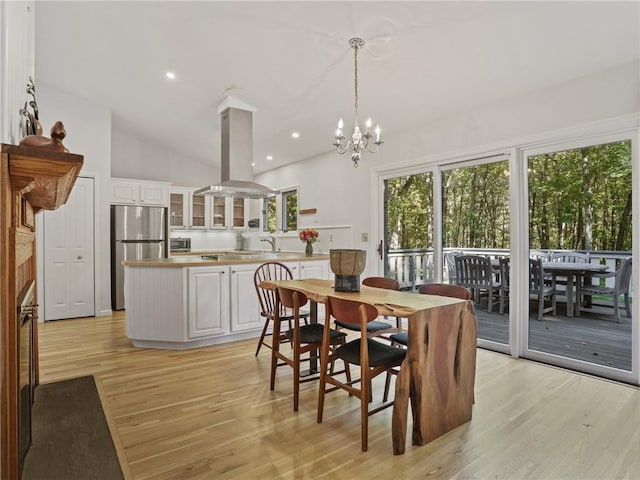 dining room with a notable chandelier, light wood-type flooring, sink, and vaulted ceiling